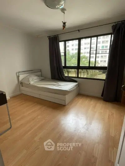 Bright bedroom with large window and wooden flooring in modern apartment