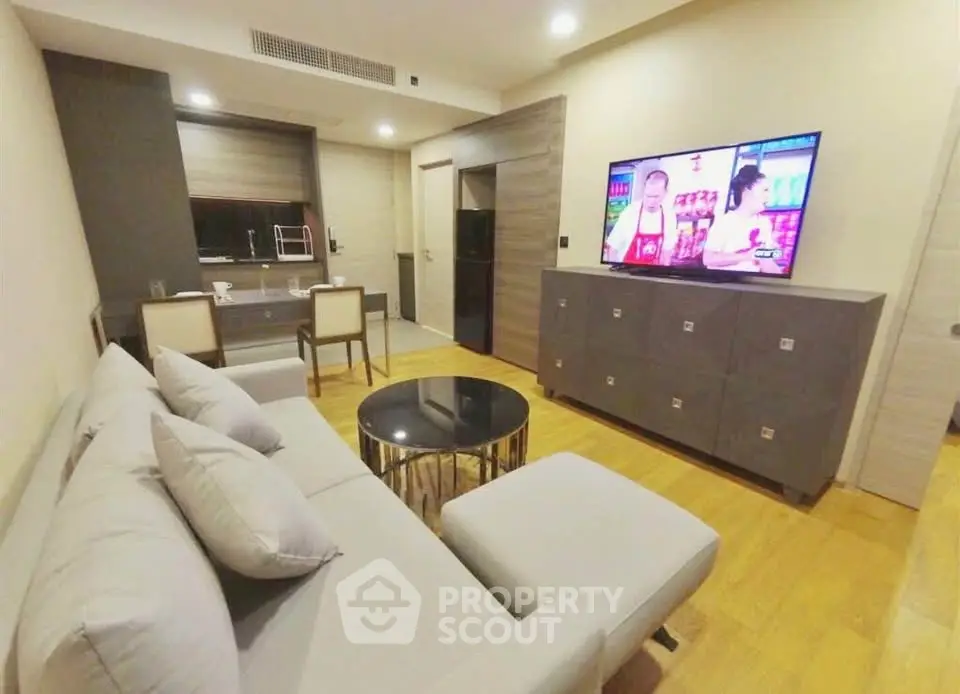 Modern living room with sleek furniture and open kitchen layout in a stylish apartment.