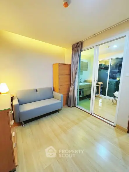 Cozy living room with modern decor and sliding glass doors leading to a compact kitchen area.