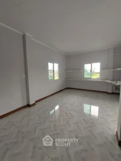 Spacious empty room with tiled flooring and large windows in a modern home.