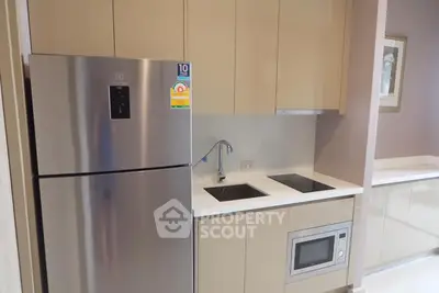 Modern kitchen with sleek cabinetry, stainless steel fridge, and built-in microwave in a compact layout.