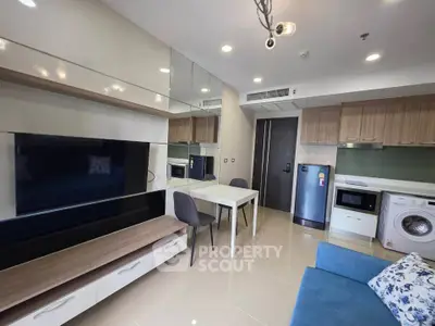 Modern living room with open kitchen, featuring sleek appliances and stylish furniture.