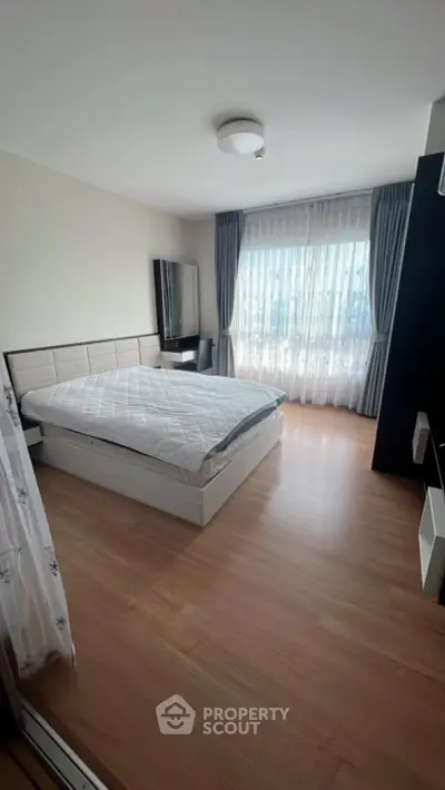 Spacious bedroom with large window and modern furnishings
