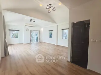 Spacious empty living room with wooden flooring and large windows for natural light.
