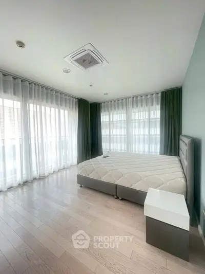 Spacious bedroom with large windows and modern decor in a luxury apartment.