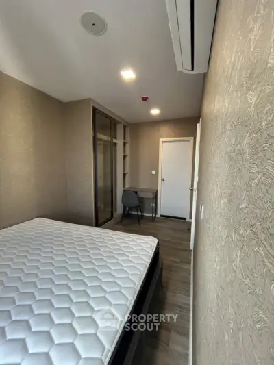 Modern bedroom with stylish decor and built-in closet, featuring a comfortable bed and workspace.