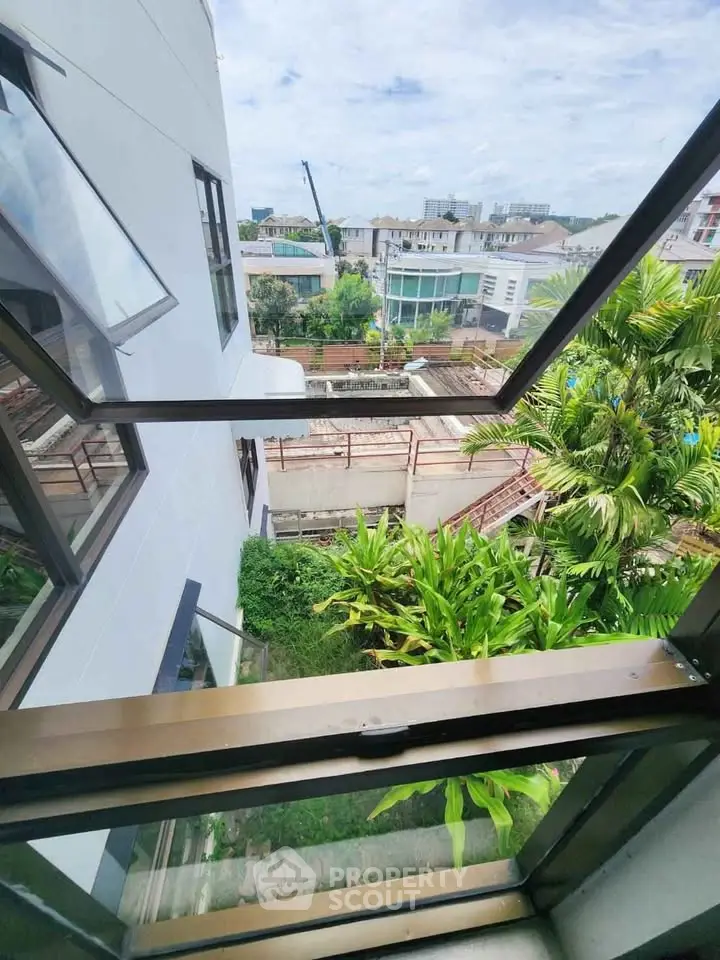 Stunning view from modern building window overlooking lush greenery and urban landscape.