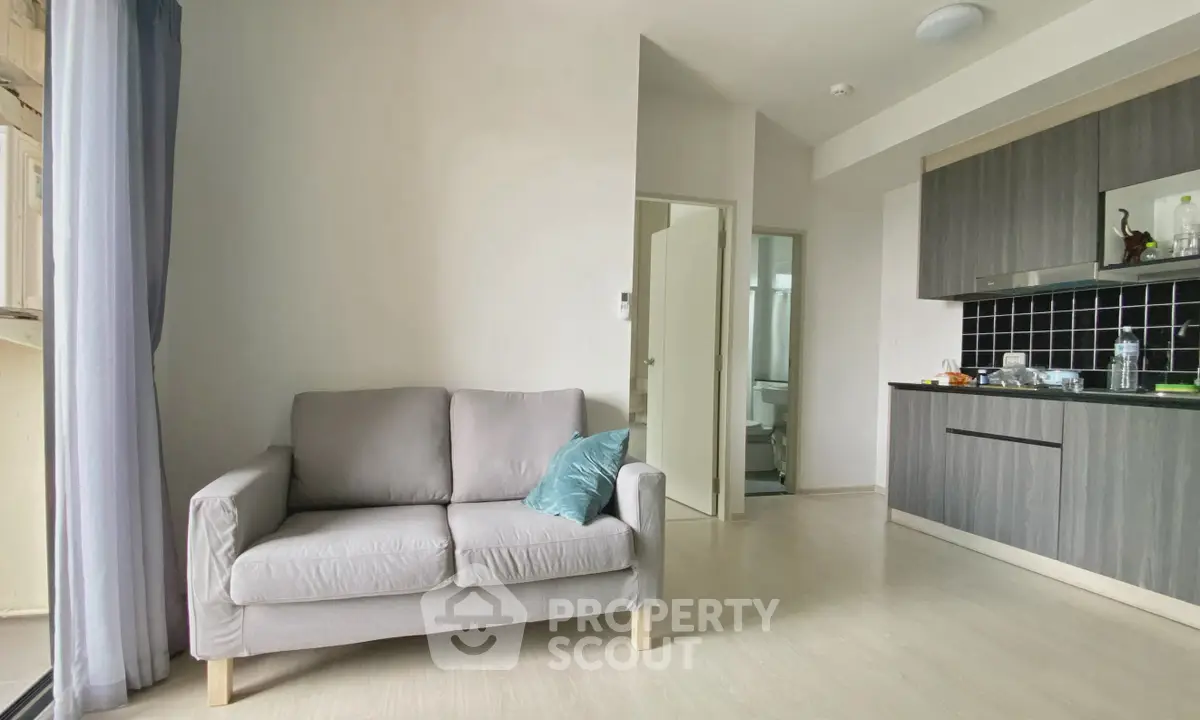 Modern living room with cozy sofa and sleek kitchen in open layout apartment.