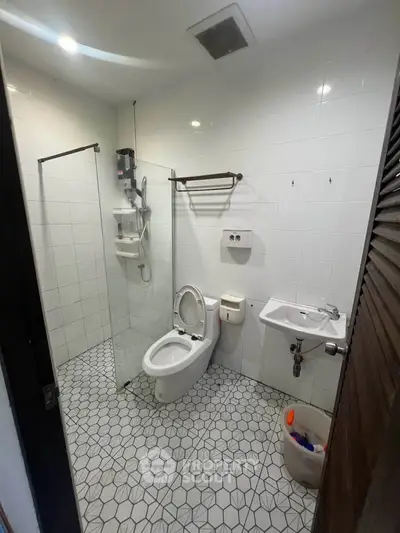 Modern bathroom with geometric tile flooring and glass shower partition