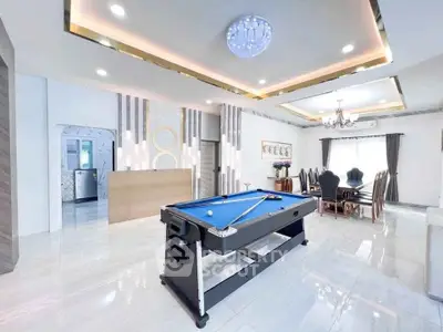 Luxurious living room with pool table and elegant dining area, modern lighting and stylish decor.
