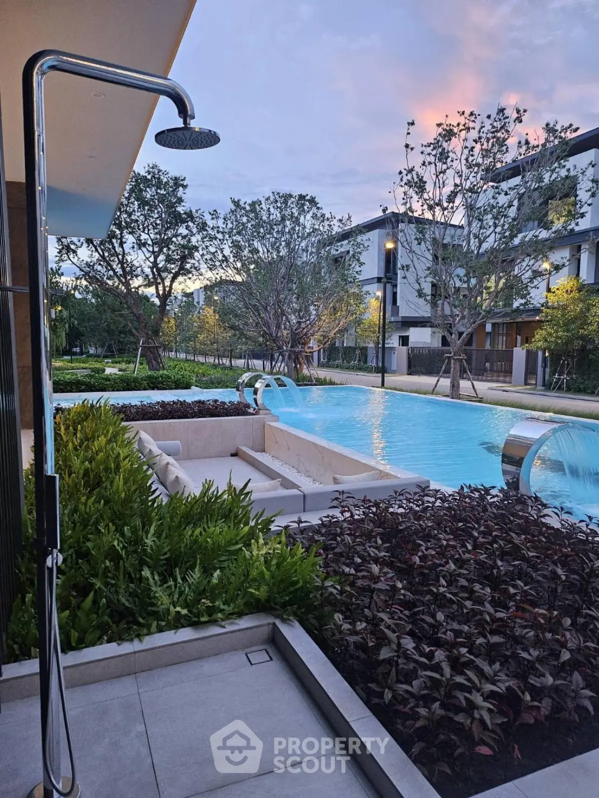 Luxurious outdoor pool area with modern shower and lush greenery