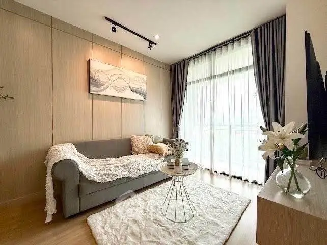 Stylish living room with cozy sofa and elegant decor, featuring large windows and natural light.