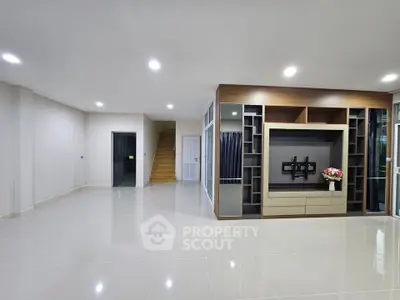 Spacious modern living room with built-in entertainment center and sleek tile flooring.