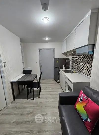 Modern kitchen with dining area in a cozy apartment, featuring sleek cabinetry and stylish backsplash.