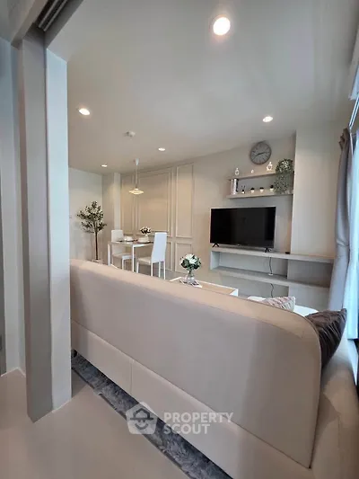 Modern living room with sleek furniture and wall-mounted TV in a bright, airy space.