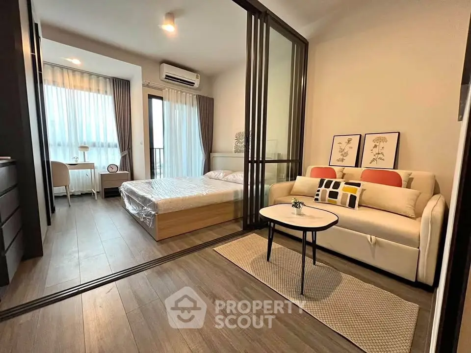 Modern studio apartment with glass partition, cozy living area, and natural light.