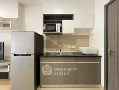 Modern kitchen with sleek cabinetry, stainless steel fridge, and built-in microwave in a stylish apartment.
