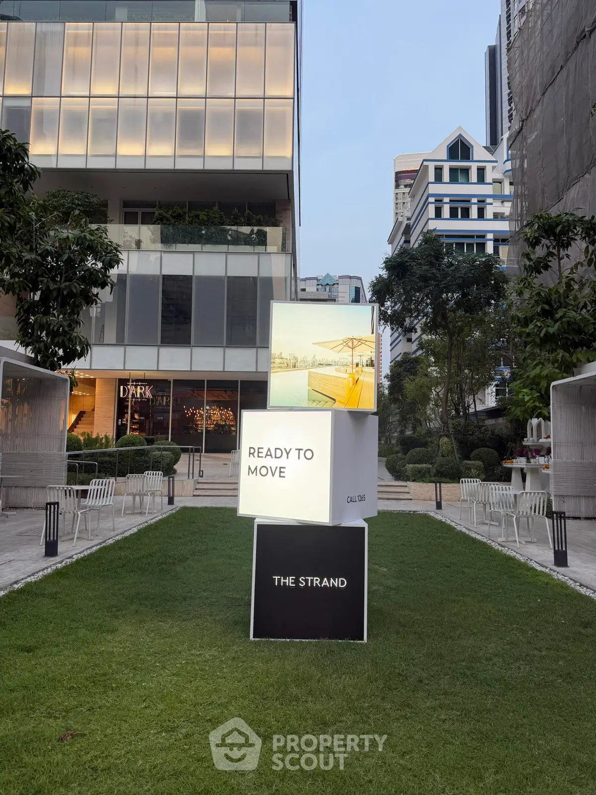 Modern urban building exterior with lush green lawn and stylish signage