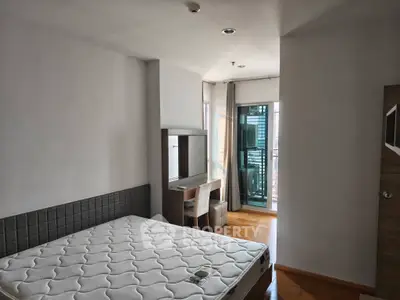 Spacious bedroom with balcony access and natural light, featuring a comfortable bed and modern decor.