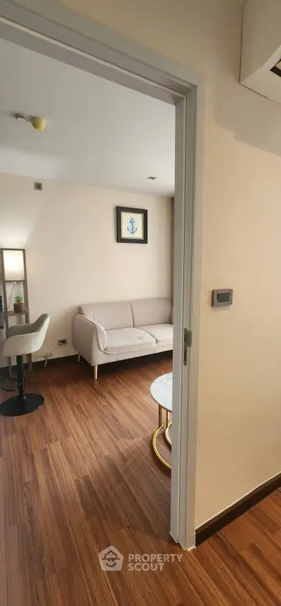 Cozy living room with modern decor and wooden flooring, featuring a comfortable sofa and stylish table.