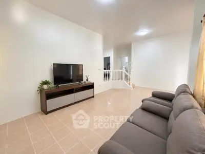 Spacious living room with modern sofa and large TV, ideal for relaxation and entertainment.