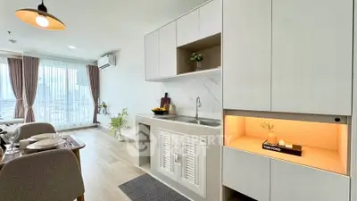 Modern open-layout kitchen with sleek cabinetry and dining area, featuring large windows and stylish decor.