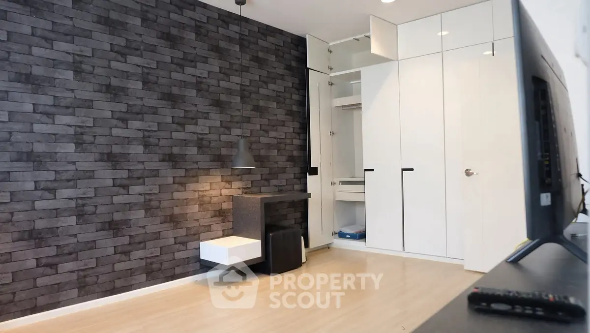 Modern minimalist living room with stylish brick accent wall and built-in storage solutions.