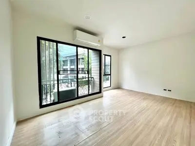 Spacious empty room with large windows and wooden flooring, ideal for customization.