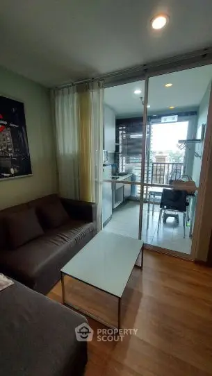Modern living room with sliding glass doors leading to a balcony, featuring cozy seating and stylish decor.