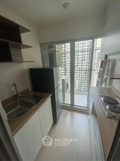 Compact kitchen with modern appliances and balcony view in urban apartment