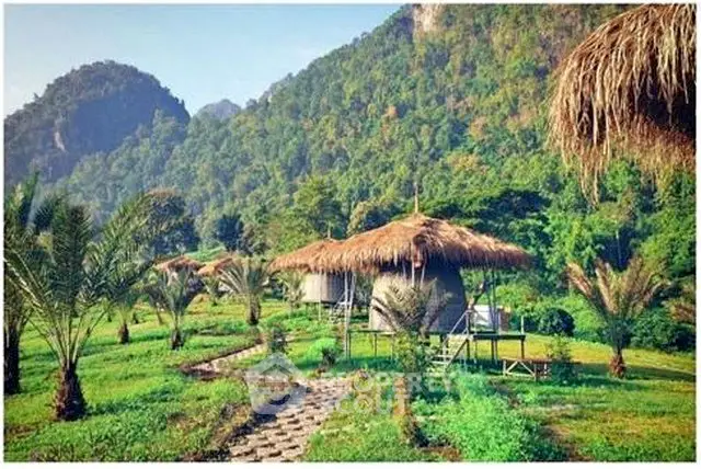 Charming eco-friendly huts with thatched roofs nestled in lush green mountains, perfect for nature retreats.