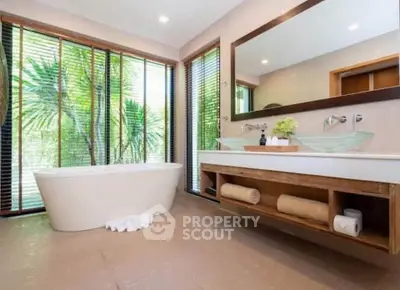 Luxurious bathroom with modern fixtures and large windows overlooking greenery.