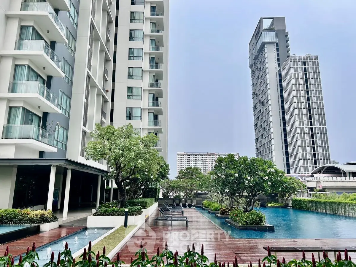 Luxurious high-rise apartment complex with stunning pool and lush greenery.