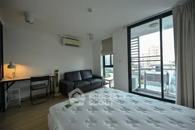 Modern bedroom with balcony view, featuring a cozy bed, sleek sofa, and work desk in a bright, airy space.