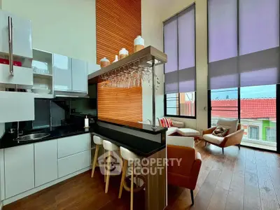 Modern living room with high ceilings and stylish kitchen bar in a contemporary apartment.