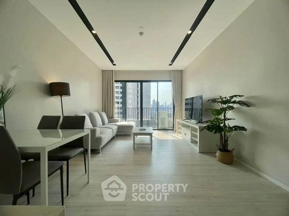 Spacious modern living room with large windows and city view, featuring sleek furniture and elegant decor.