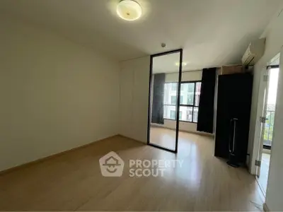 Spacious bedroom with large window and mirrored wardrobe in modern apartment