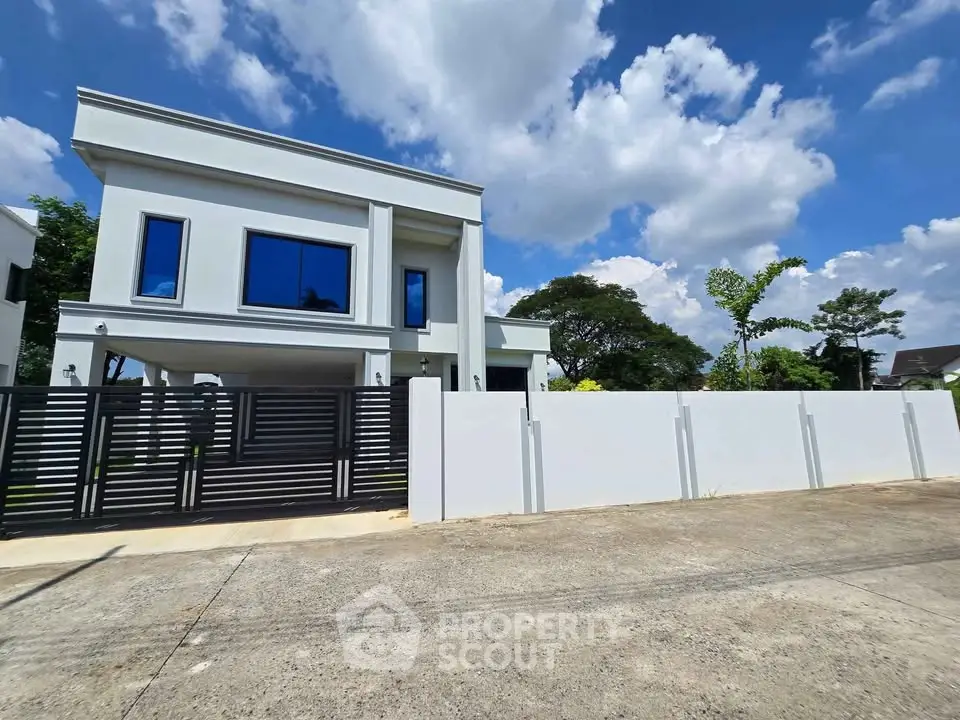 Modern two-story house with sleek design and large windows under a bright blue sky.