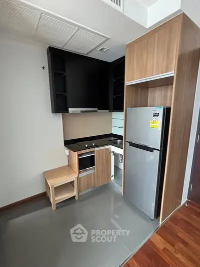 Modern compact kitchen with sleek cabinetry and stainless steel appliances in a stylish apartment.