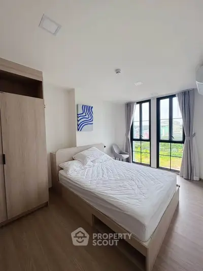 Modern bedroom with large windows and minimalist decor in a bright apartment.