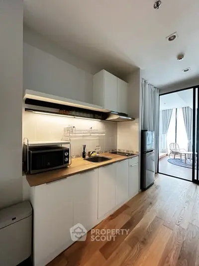 Modern kitchen with sleek cabinetry and wooden flooring in a stylish apartment