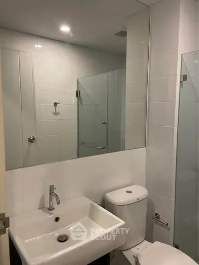 Modern bathroom with sleek fixtures and large mirror in contemporary apartment.