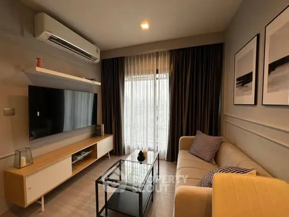 Modern living room with stylish decor, large TV, and cozy seating area.