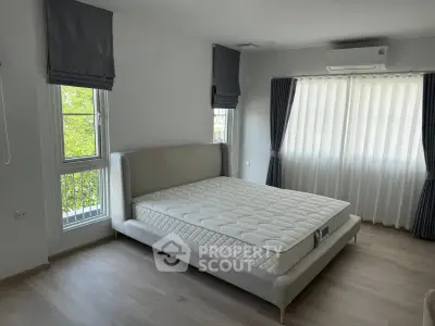 Spacious bedroom with modern bed and large windows offering natural light.