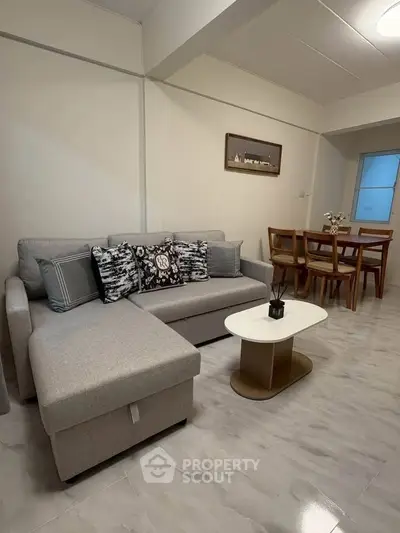 Modern living room with stylish gray sofa and elegant dining area, perfect for cozy gatherings.