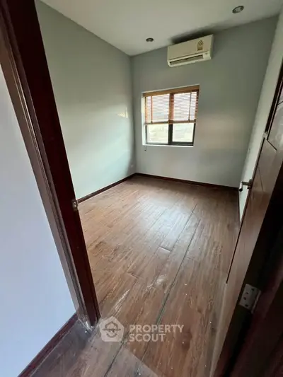 Spacious bedroom with wooden flooring and air conditioning, perfect for a cozy retreat.