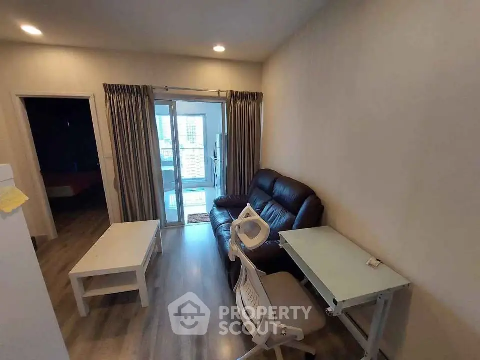 Cozy living room with modern furniture and balcony view in urban apartment.