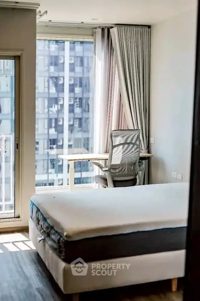 Modern bedroom with large window and study desk, offering a bright and airy atmosphere.