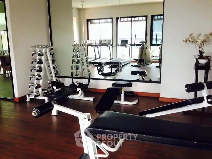 Modern gym with state-of-the-art equipment and large mirrors in a residential building.