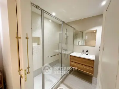 Modern bathroom with glass shower enclosure and sleek wooden vanity.